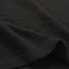 Black slub knit fabric close-up with subtle texture and fine heather-like pattern
