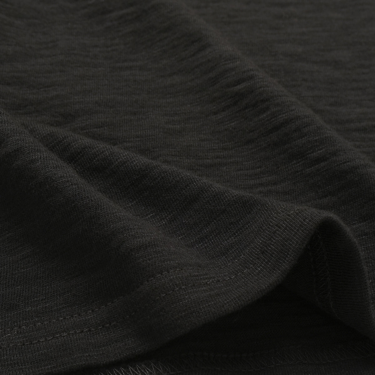 Black slub knit fabric close-up with subtle texture and fine heather-like pattern