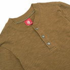Olive henley neckline detail with short button placket and greenish-blue buttons