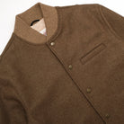 Brown stadium jacket with snap placket, chest pocket, and ribbed collar