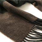 Close-up of dark green and brown striped scarf with textured weave and fringe