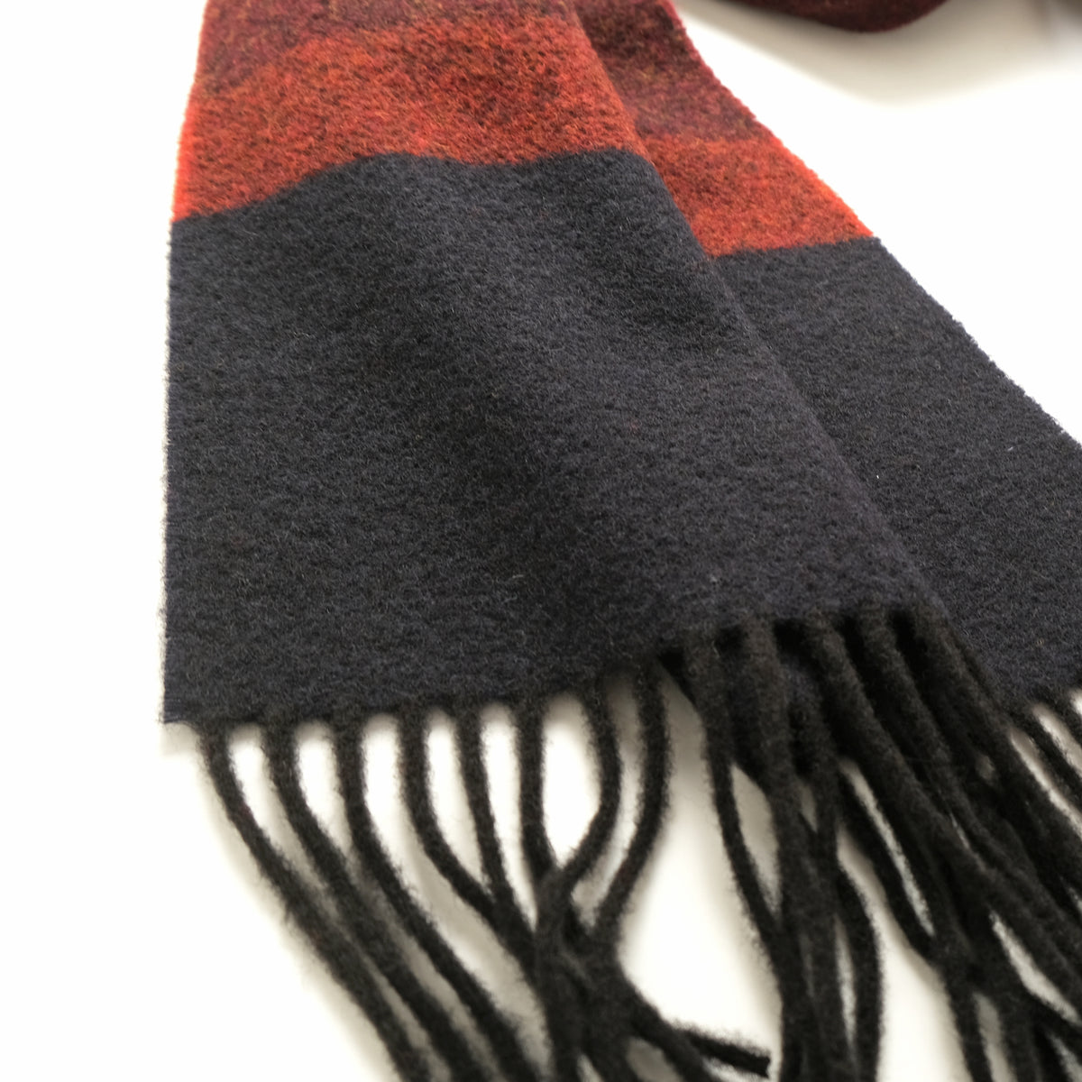 Maroon and black striped scarf close-up with textured weave and fringe