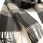 Close-up of charcoal plaid scarf with cream-and-gray checks and fringed hem