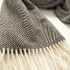 Charcoal herringbone scarf detail with textured weave and white fringe