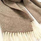 Taupe-brown herringbone scarf close-up with soft white fringe edge