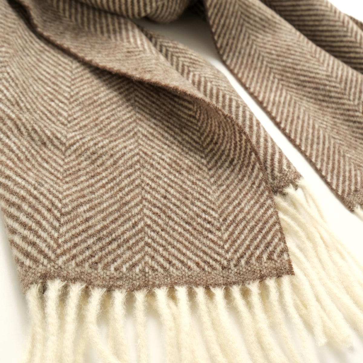 Taupe-brown herringbone scarf close-up with soft white fringe edge