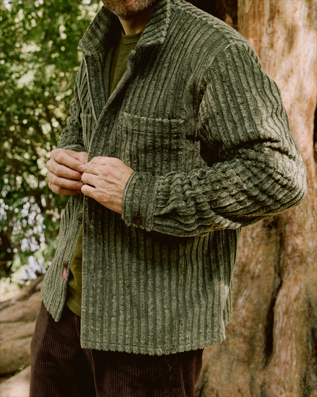 Olive corduroy club shirt on model, long sleeves, buttoned front, chest pocket