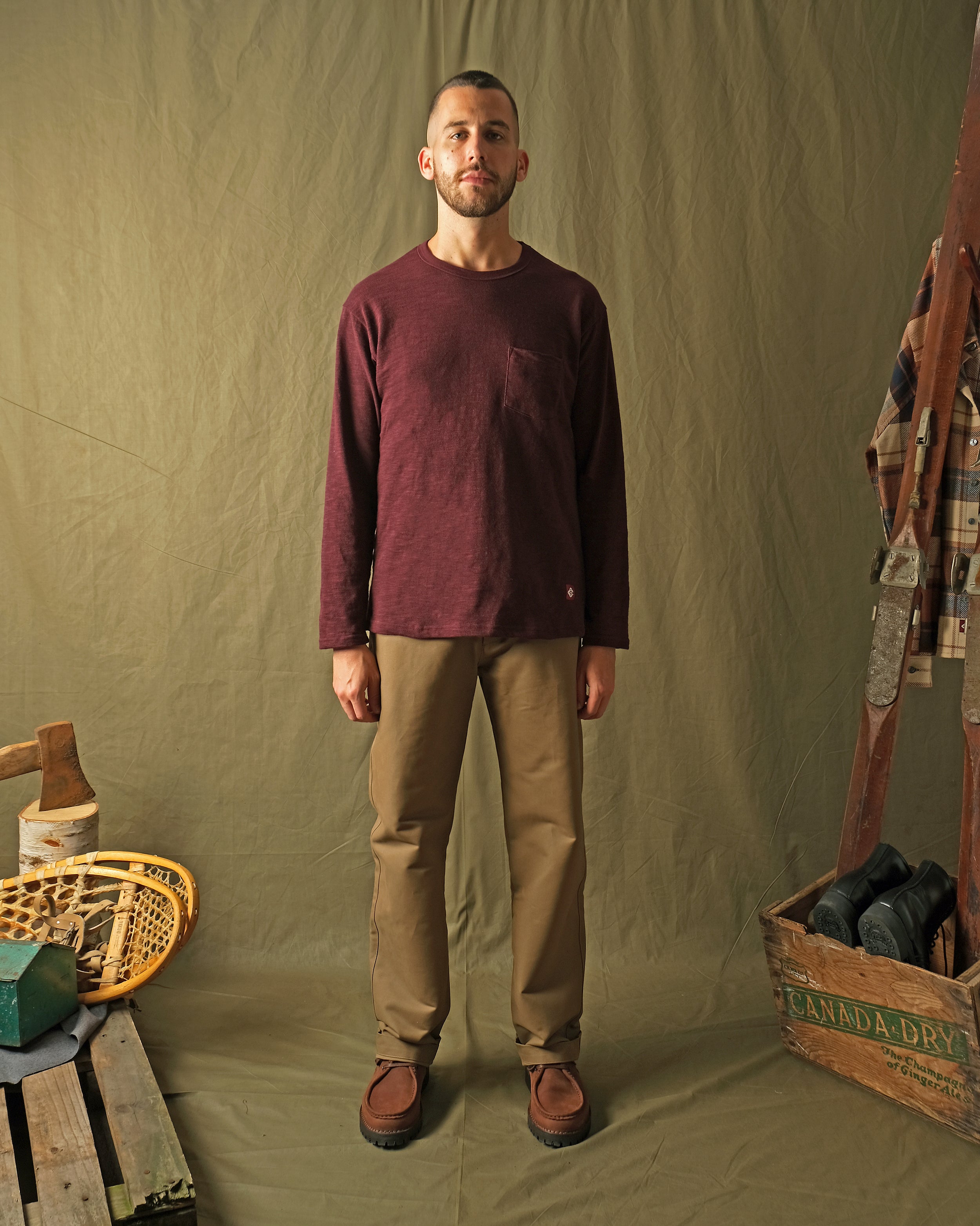 Maroon long-sleeve T-shirt with chest pocket and crew neck, worn with trousers.