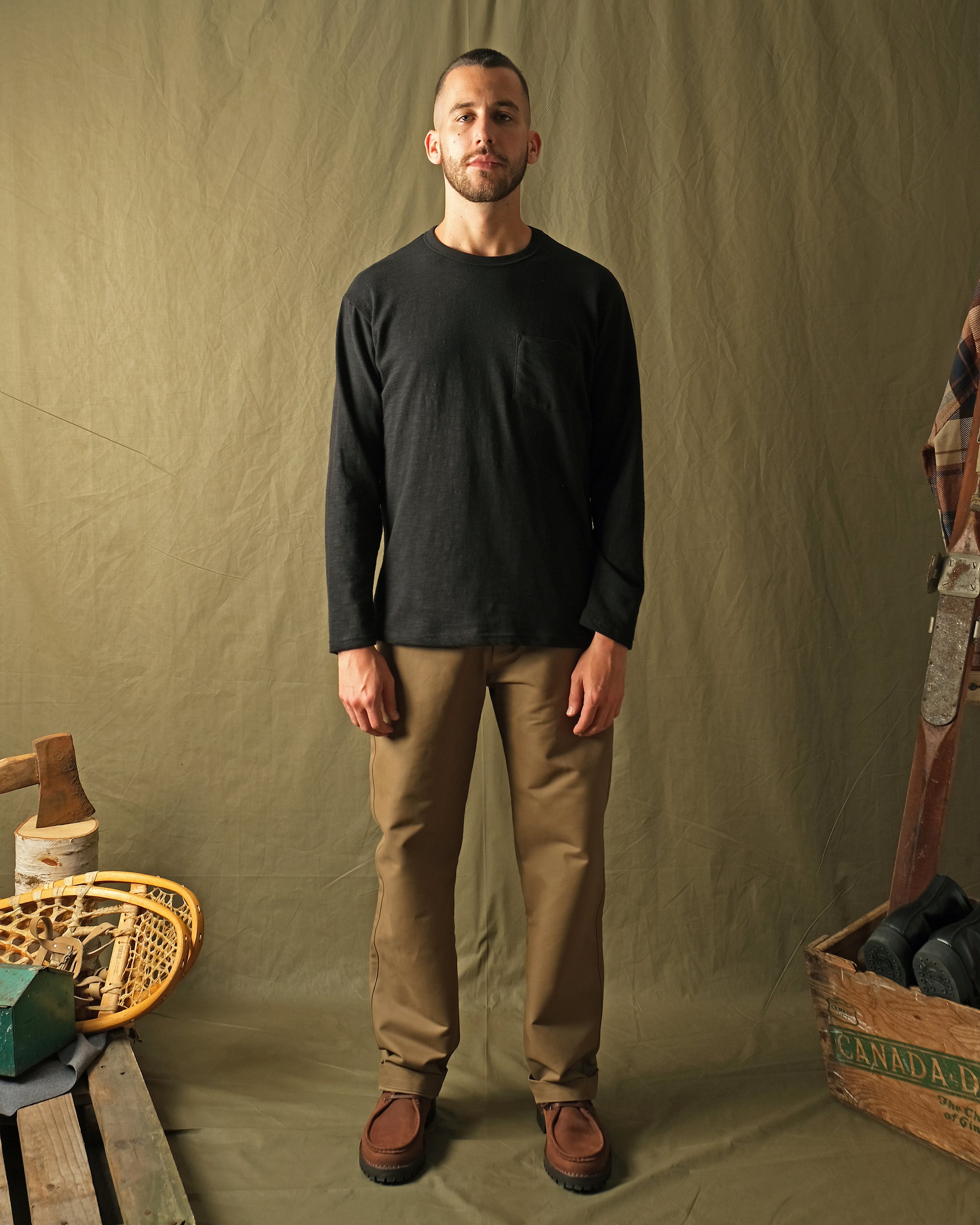 Black long-sleeve pocket T-shirt worn by model, crew neck, sleeves down
