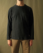 Black long-sleeve pocket T-shirt on model, crew neck and textured knit fabric