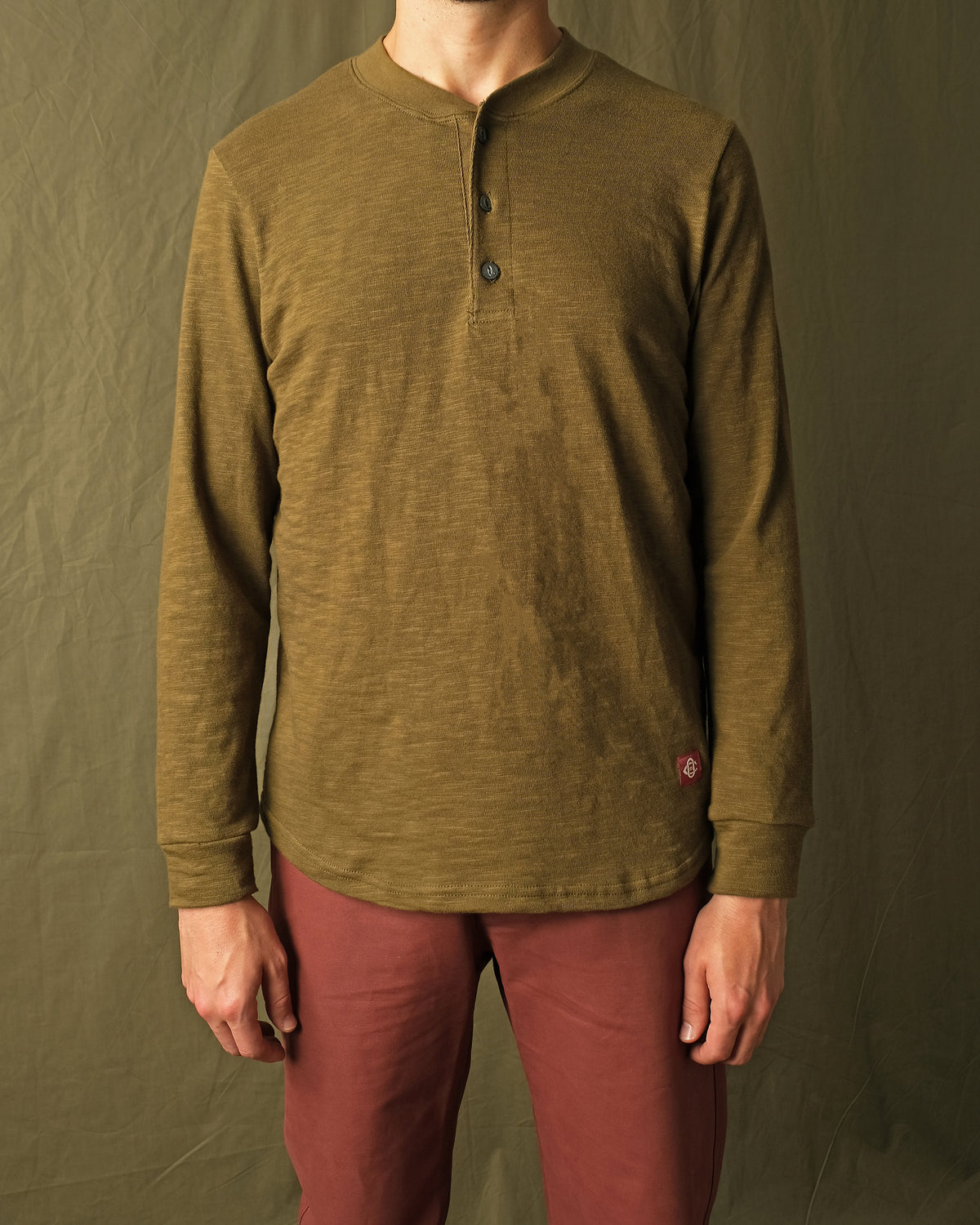 Olive long-sleeve henley shirt on model, button placket at center front