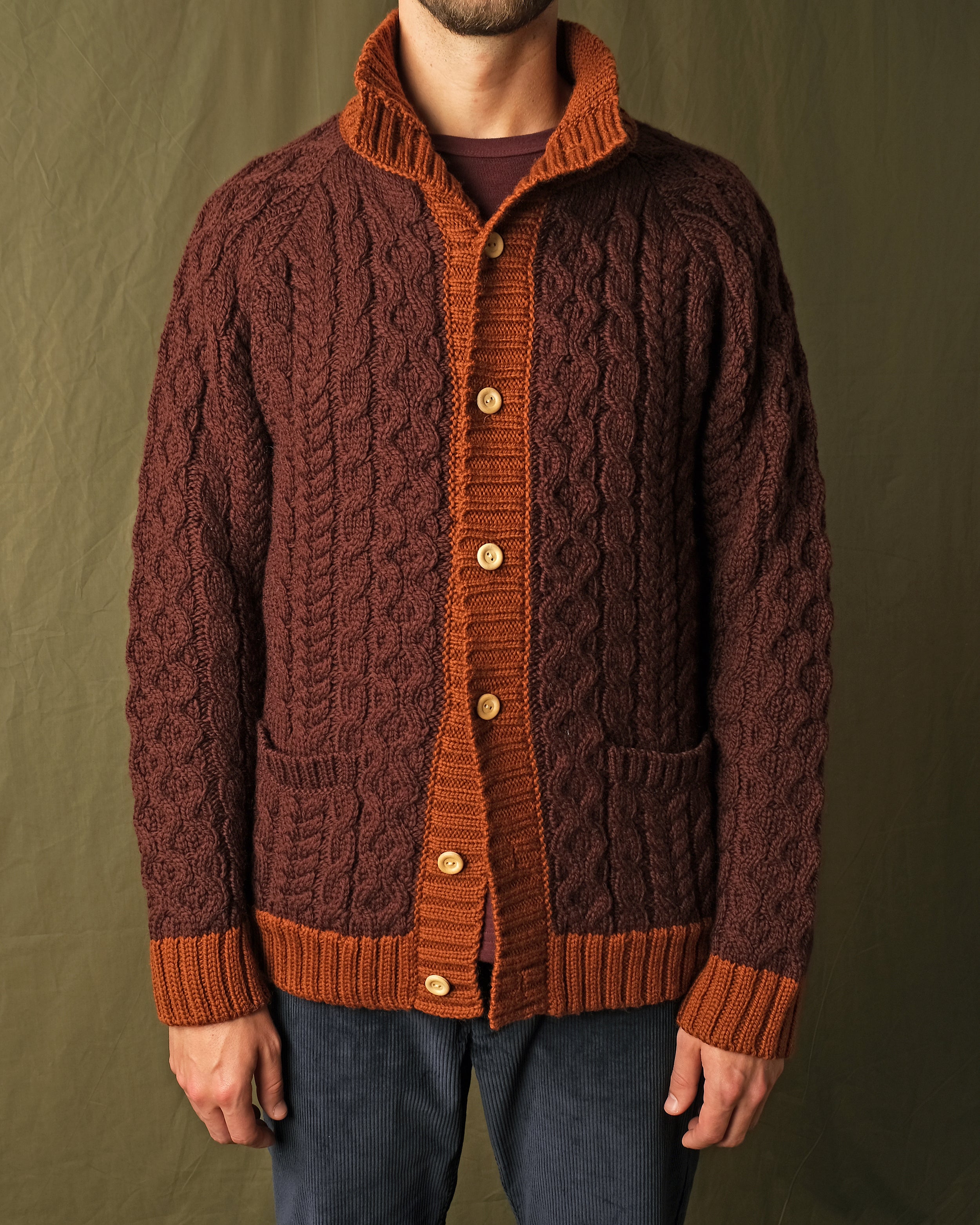 Dark maroon cable-knit mock neck cardigan with orange buttons, placket, and patch pockets