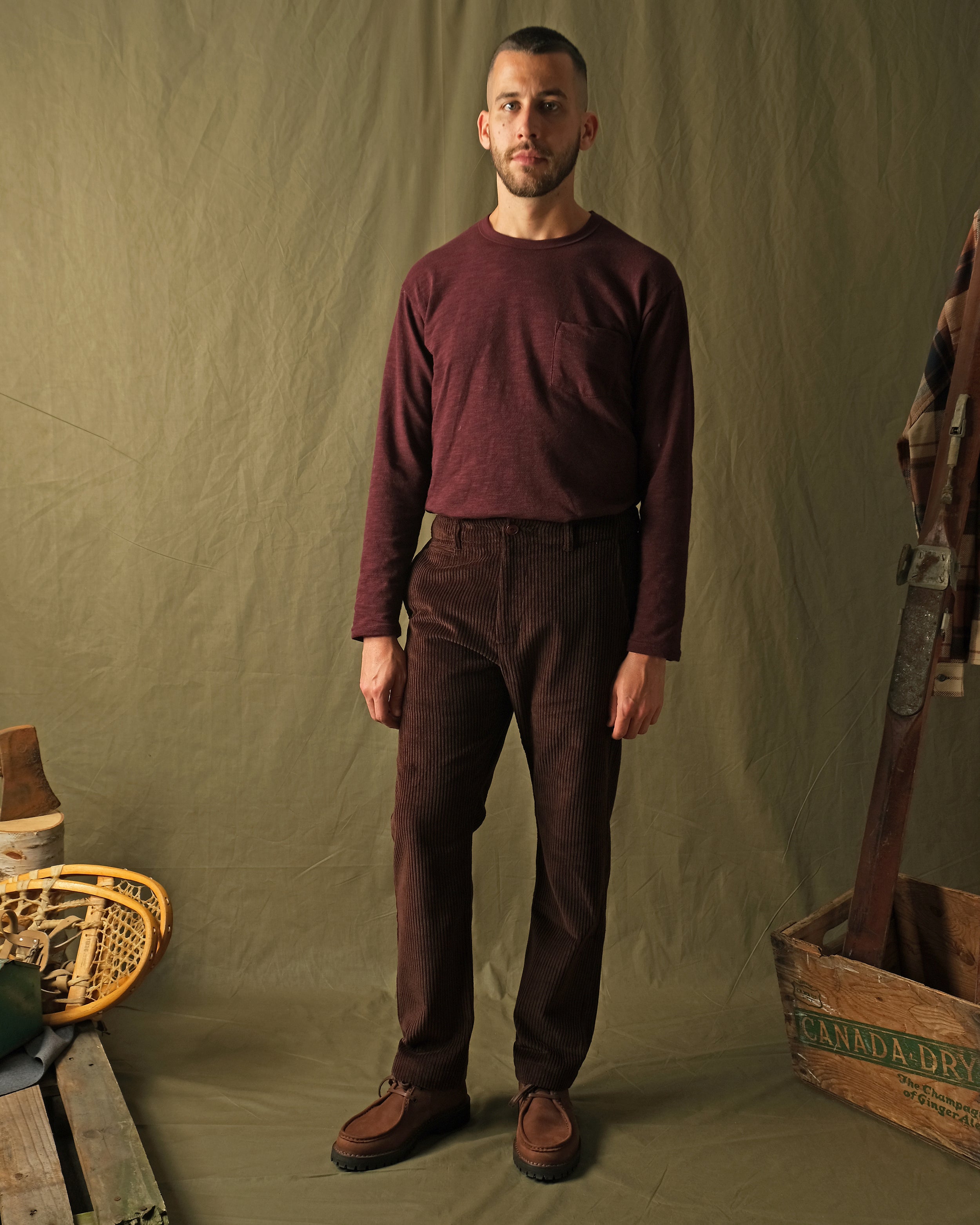 Dark brown corduroy camp pants on model, relaxed wide leg silhouette.