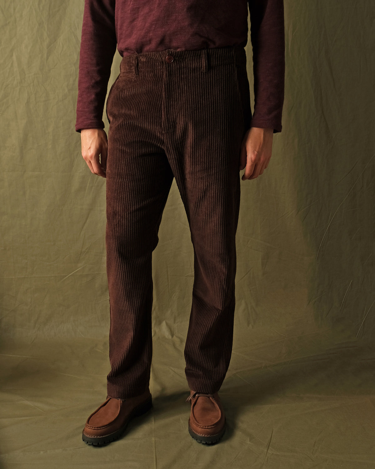 Dark brown corduroy camp pants with wide leg and cuffed hem on model.