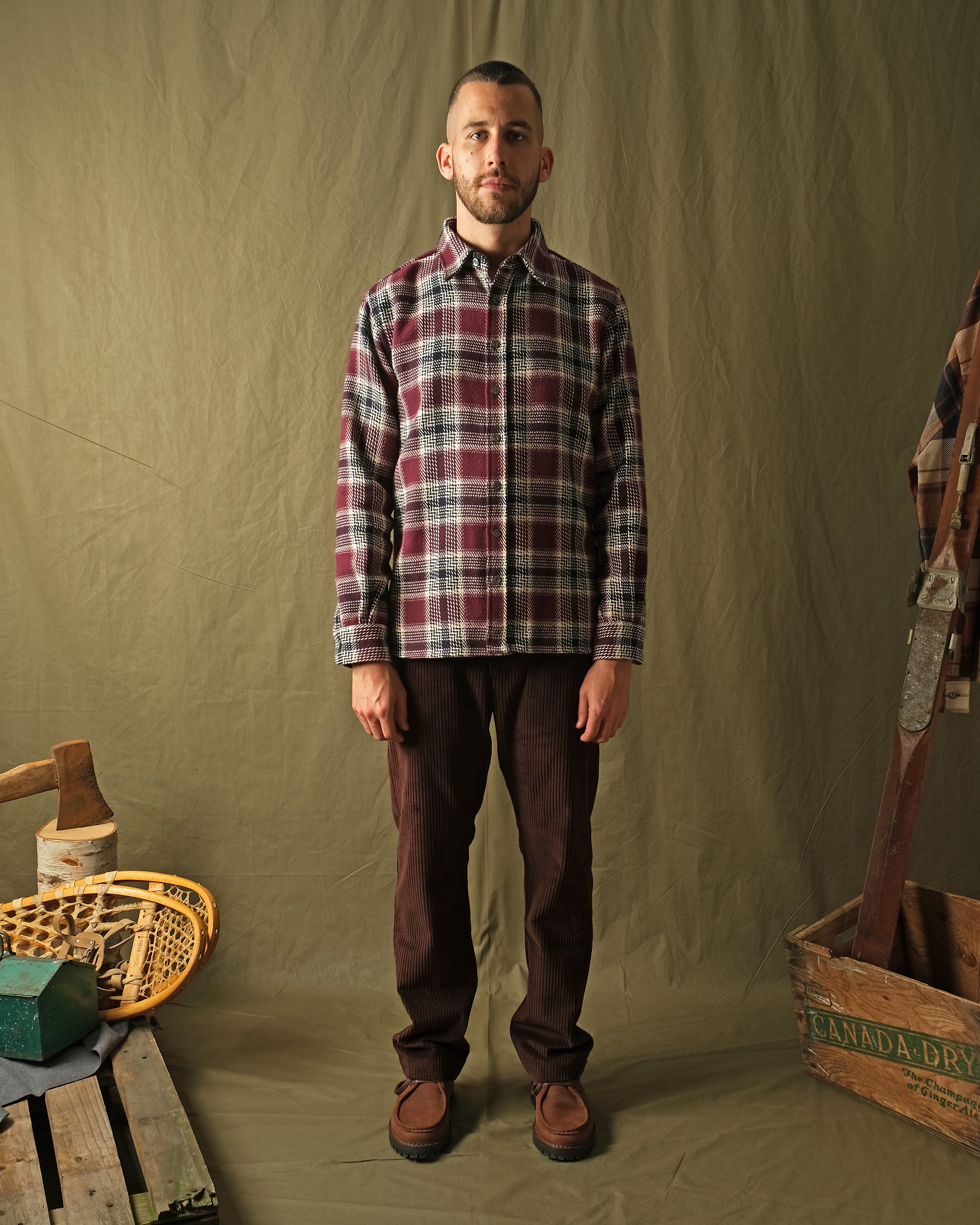 Maroon plaid button-up shirt with long sleeves worn with dark pants