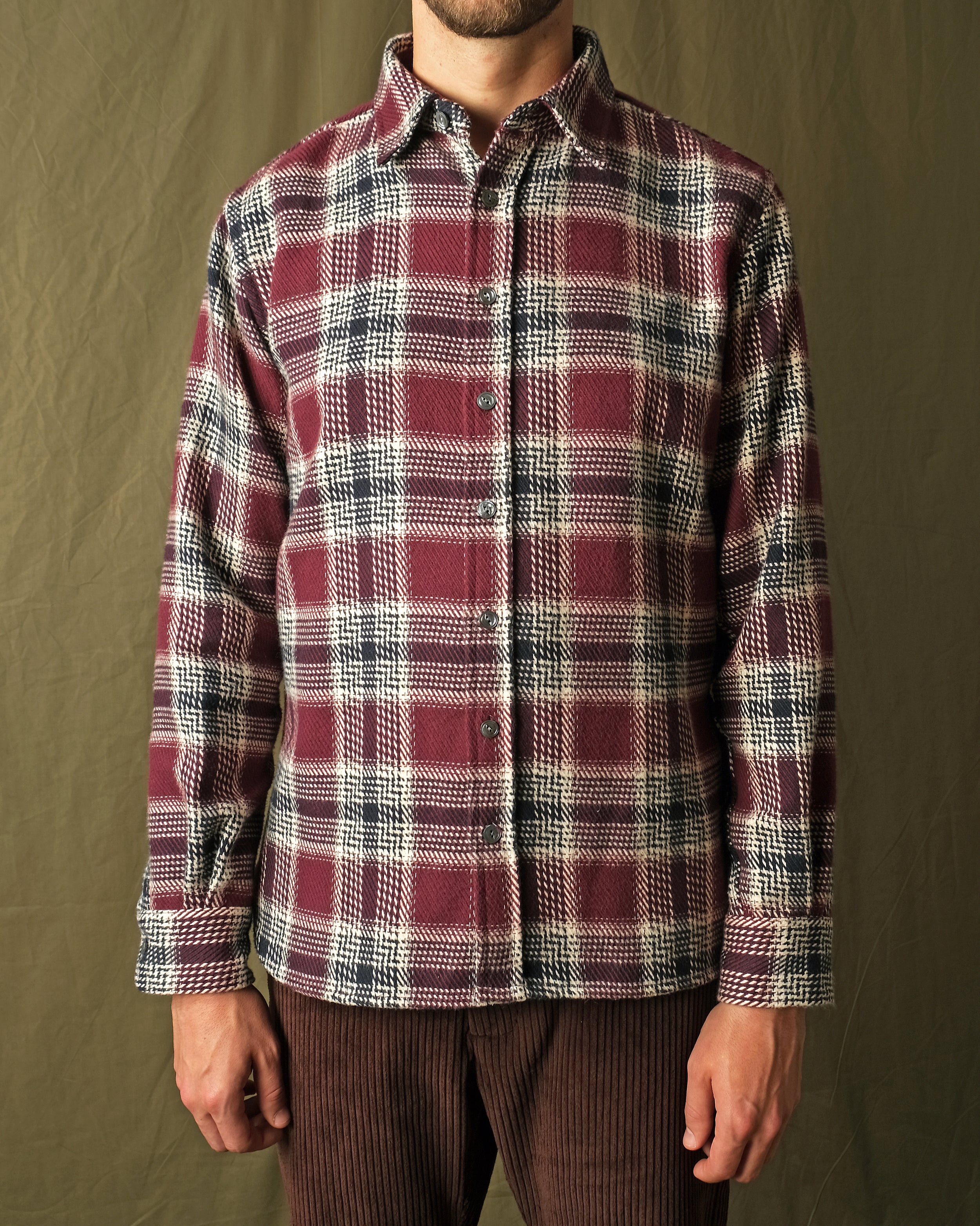 Maroon plaid button-up shirt worn with dark trousers