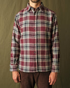 Maroon plaid button-up shirt worn with dark trousers