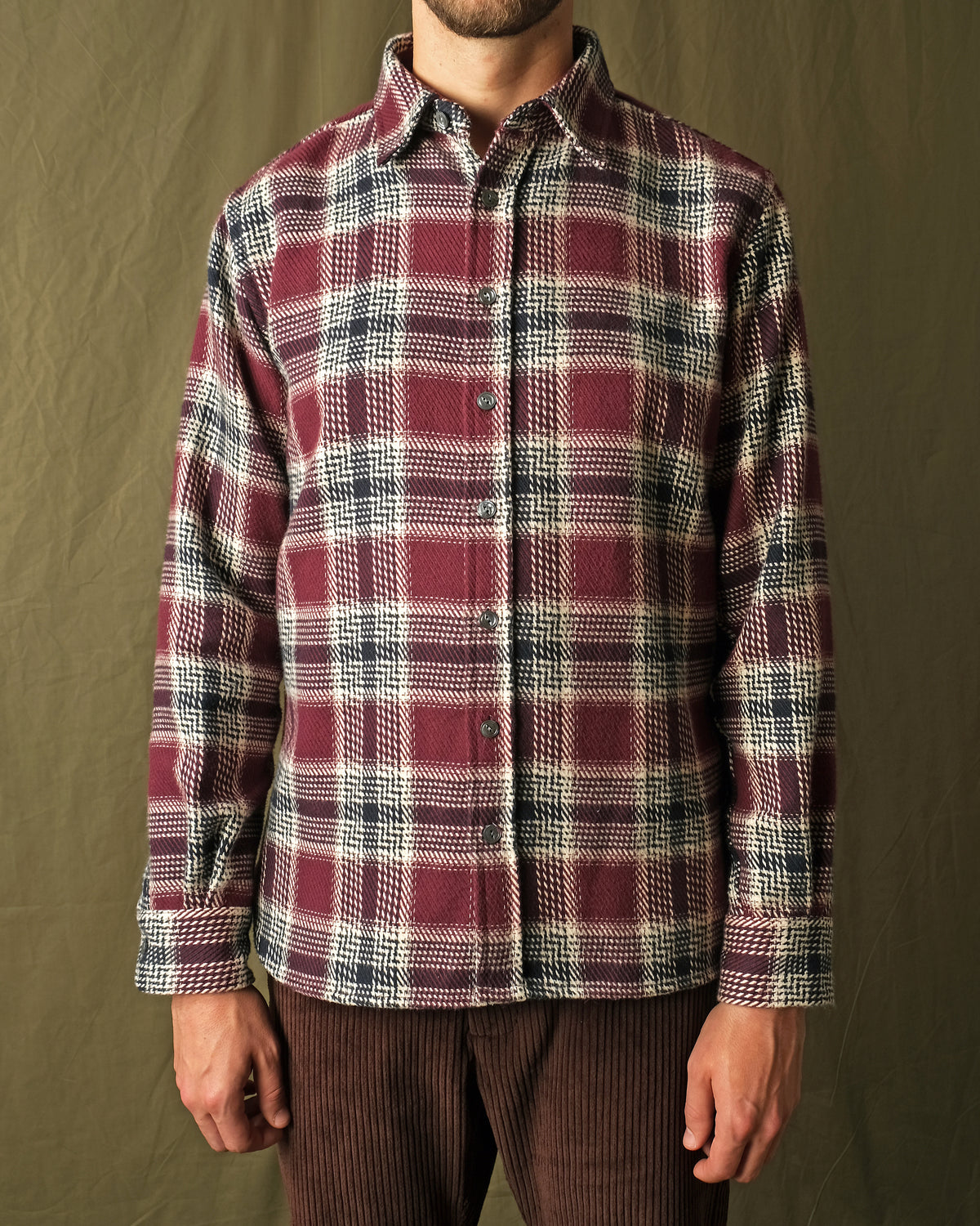 Maroon plaid button-up shirt worn with dark trousers