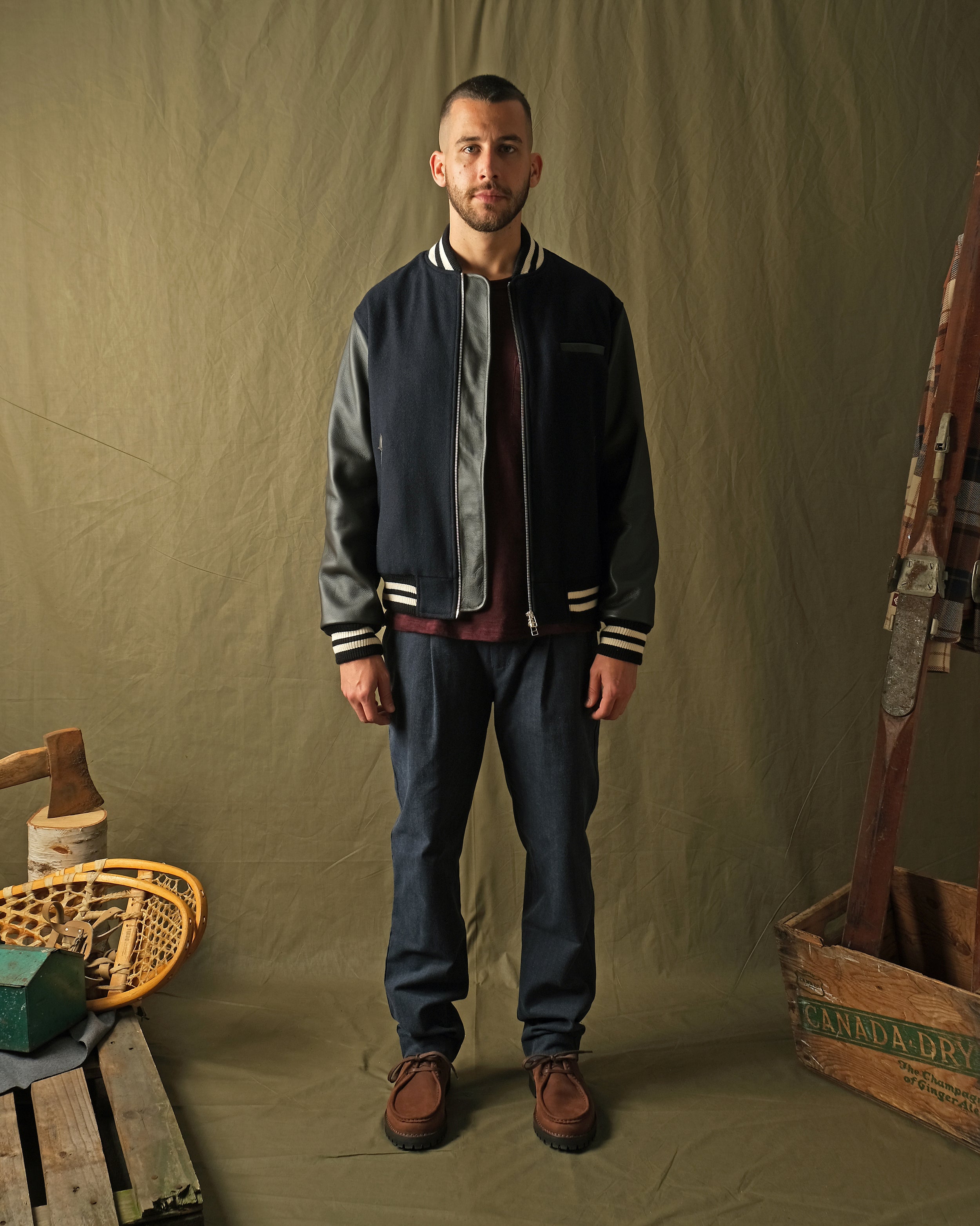Navy bomber jacket worn with dark pants; ribbed cuffs and hem with striped trim