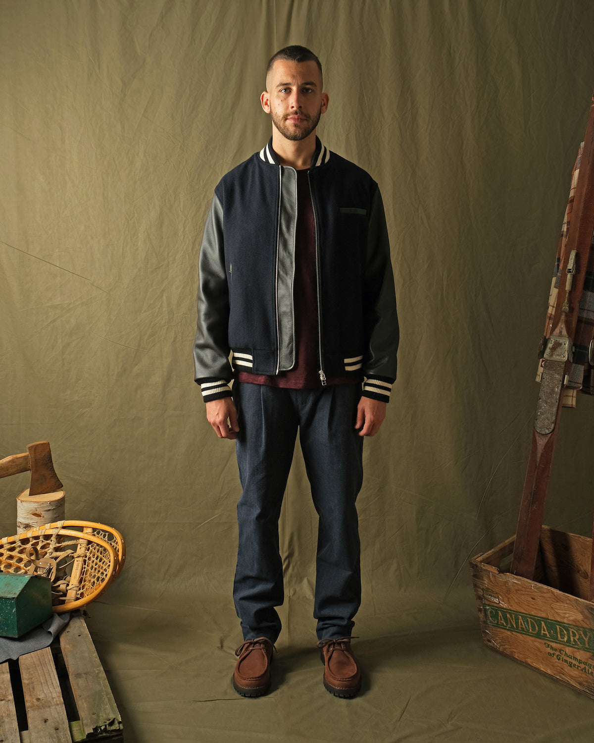 Navy bomber jacket worn with dark pants; ribbed cuffs and hem with striped trim