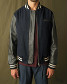 Navy bomber jacket with leather-look sleeves, striped cuffs, and front zipper
