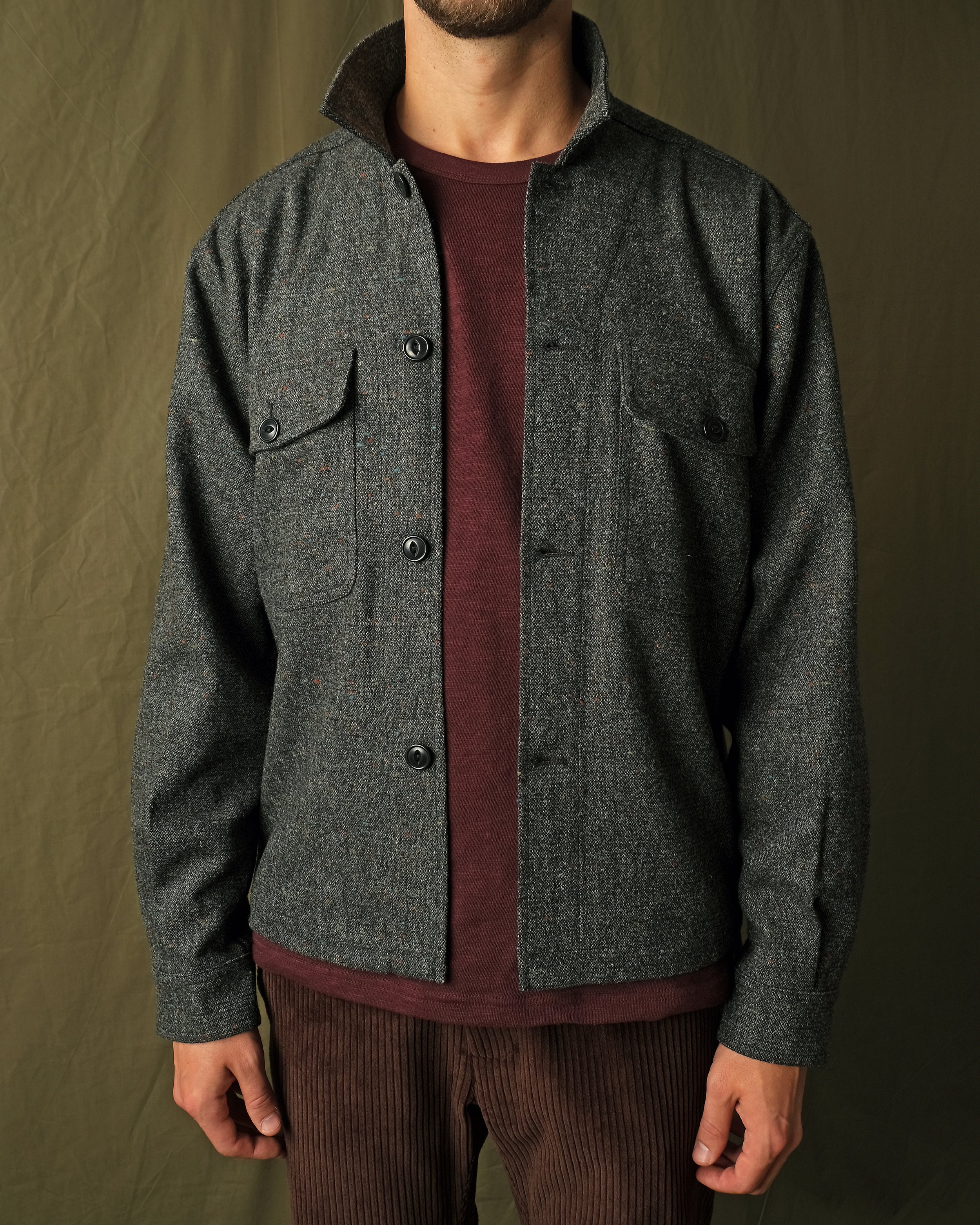 Charcoal fleck wool camp shirt with camp collar and two flap chest pockets, buttoned.
