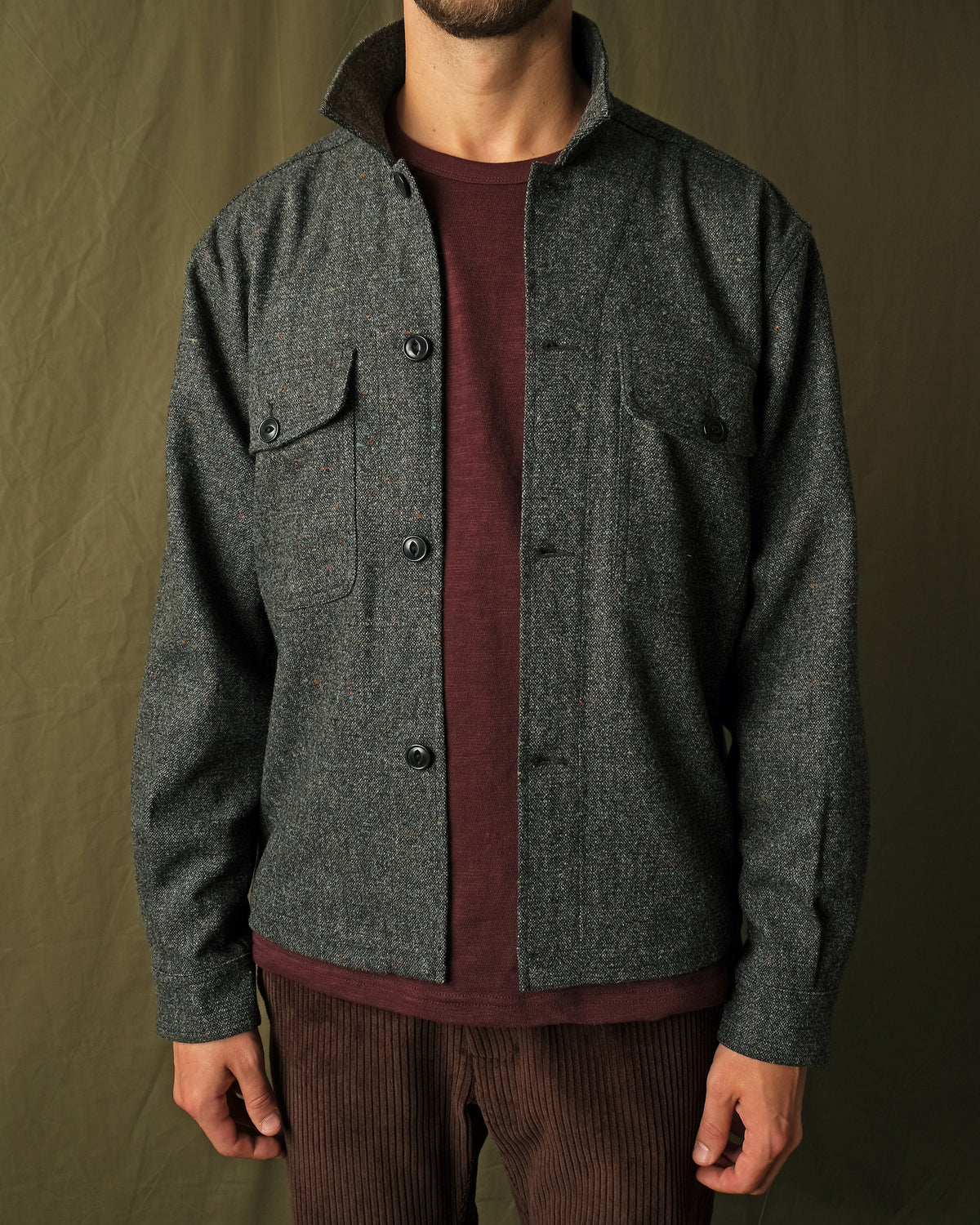 Charcoal fleck wool camp shirt with camp collar and two flap chest pockets, buttoned.