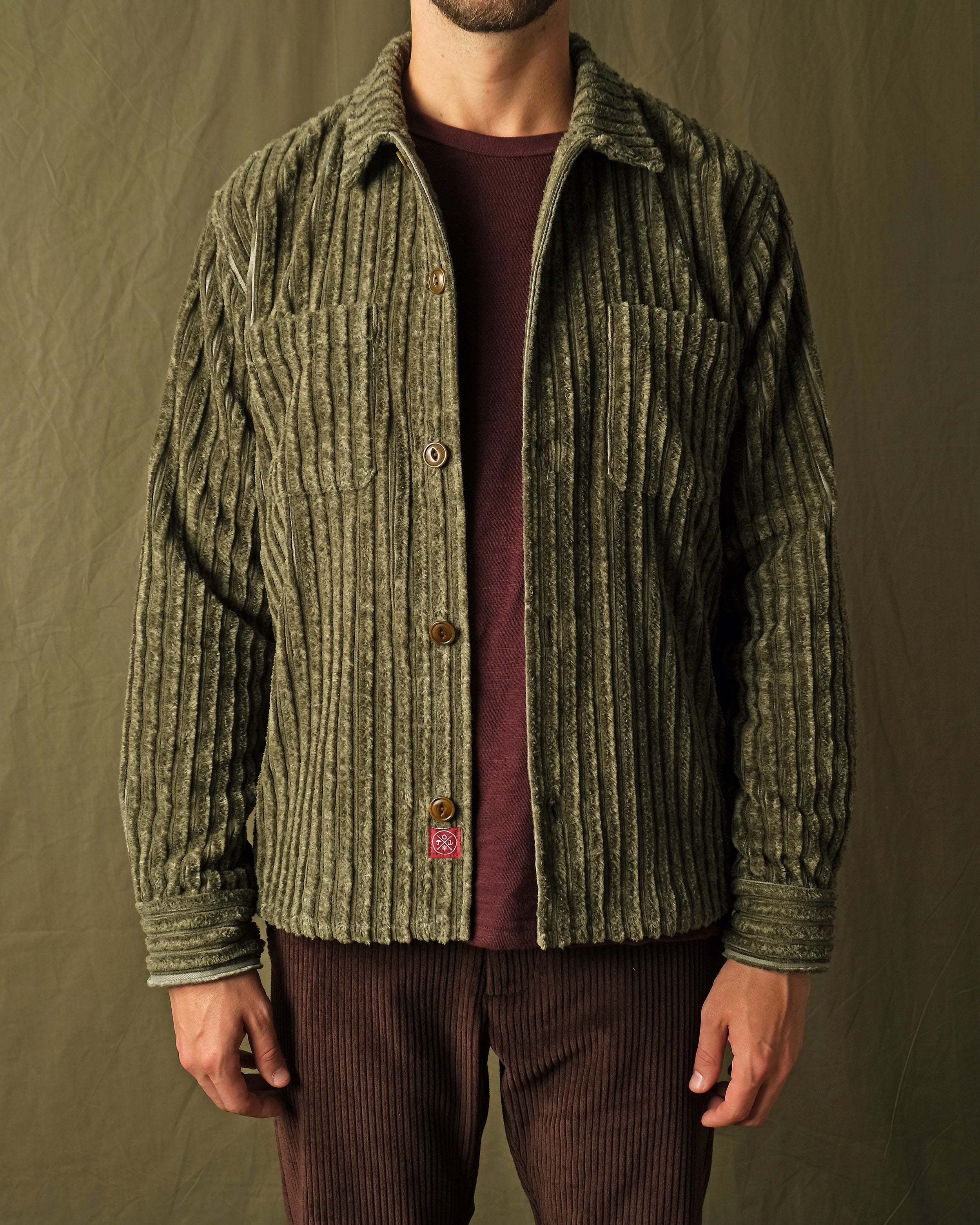 Olive jumbo corduroy club shirt on model, long sleeves, button-front, chest pocket