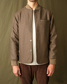 Brown stadium jacket close-up with snap buttons, stand collar, and chest pocket