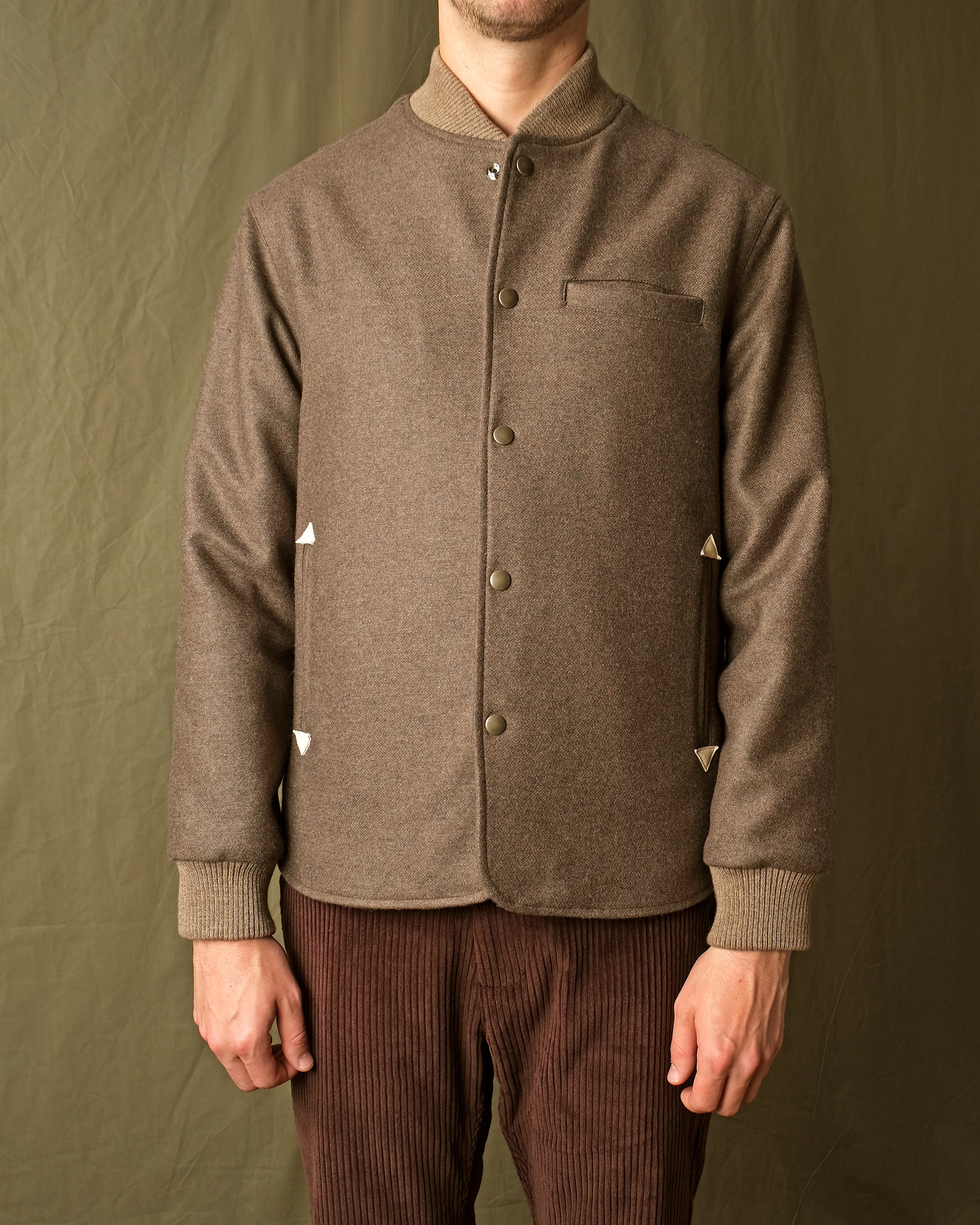 Brown stadium jacket with snap button front, stand collar, chest pocket, ribbed cuffs