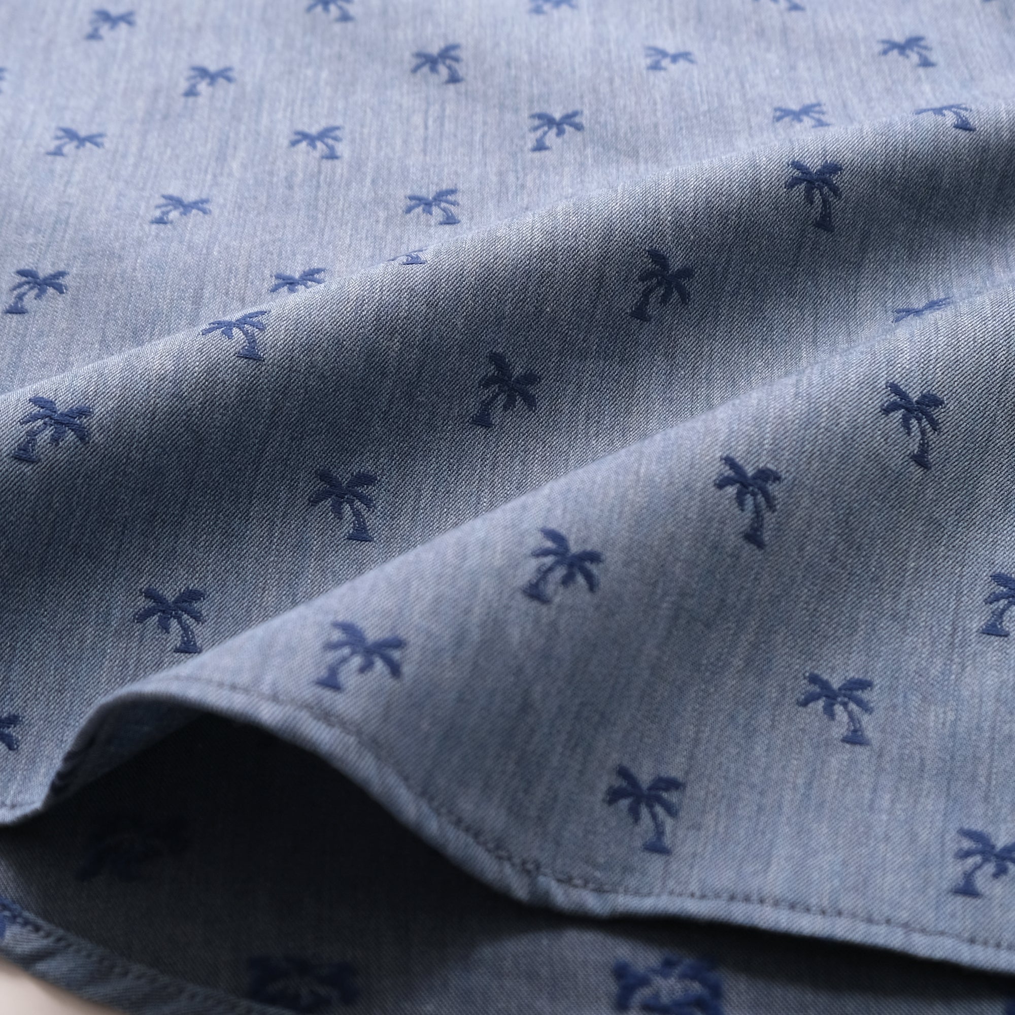 Light blue fabric with navy palm print, close-up of sleeve hem